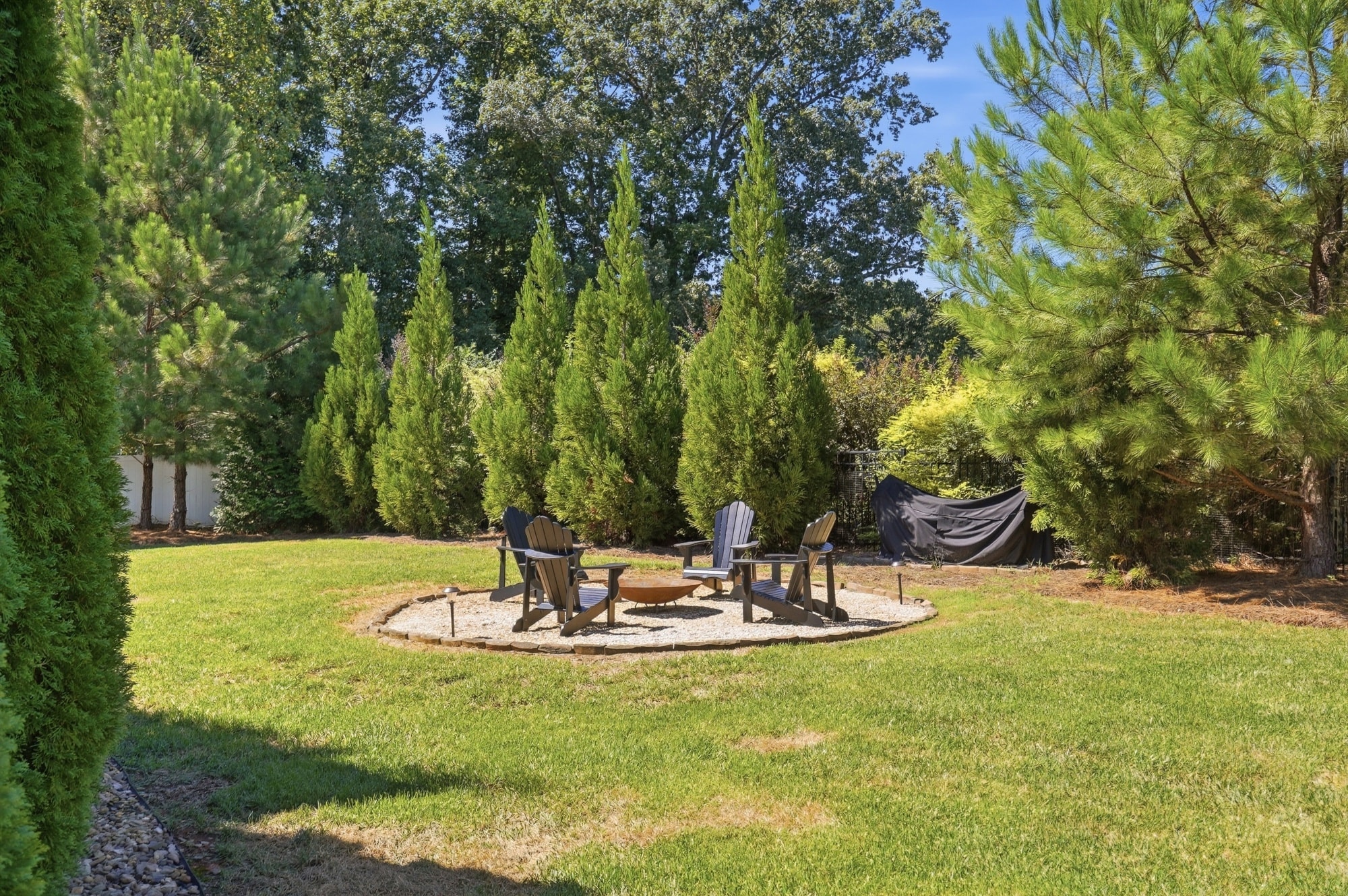 Fire pit seating area surrounded by mature evergreens at 912 Manorwood Drive, Waxhaw NC